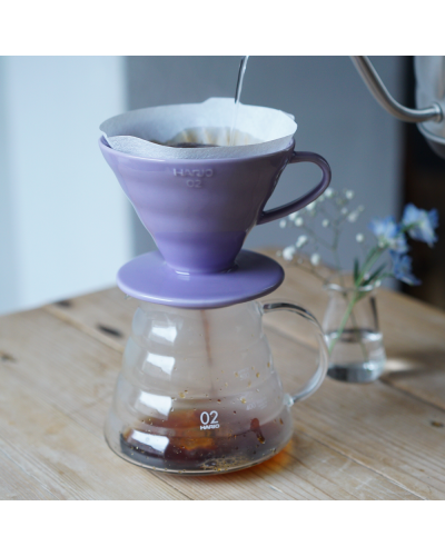 Hario V60 Dripper Cerámica 02- Lila con jarra en mesa con flores.