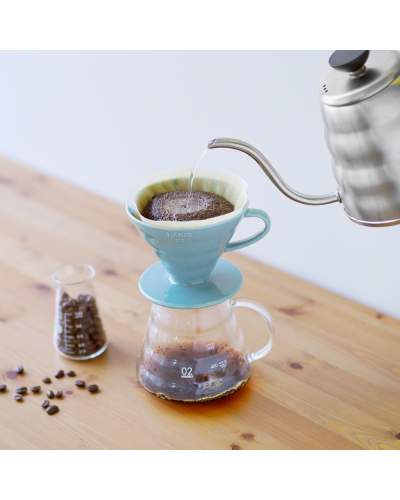 Hario V60 Dripper Cerámica 02-Azul Pastel con jarra y granmos de cafe en la mesa