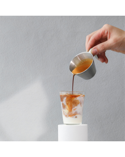 MHW3Bomber Stainless Steel Measuring Cup 100ml pouring into glass of milk.