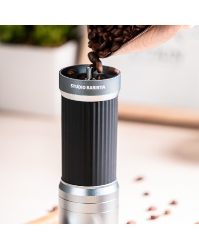 Pouring coffee beans into Studio Barista Manual Coffee Grinder with Foldable Handle Grey
